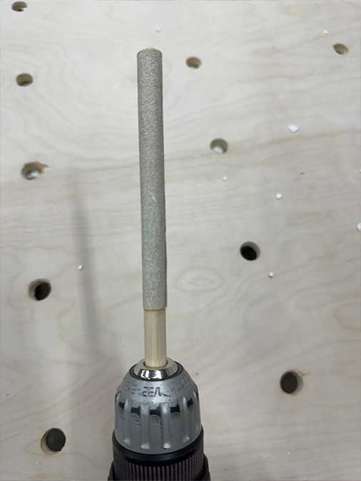 Cordless drill with a sanding dowel attached, ready to work on small holes