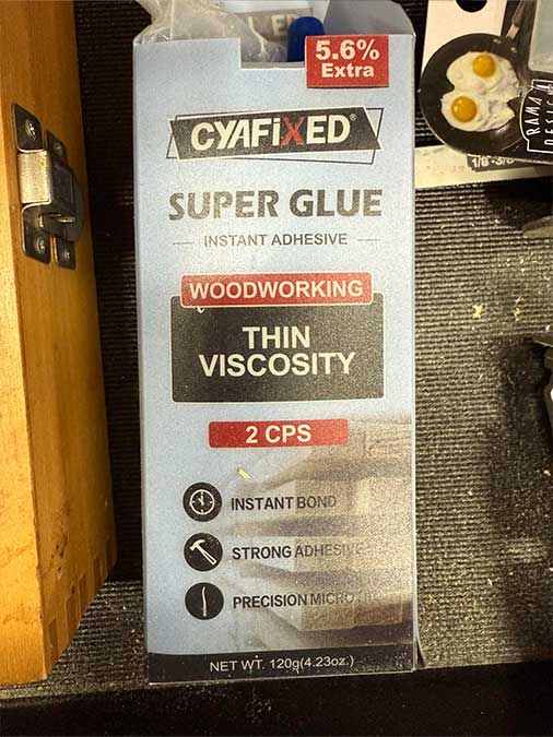 Glue of choice in the package next to sandpaper ready to be wrapped on the dowel